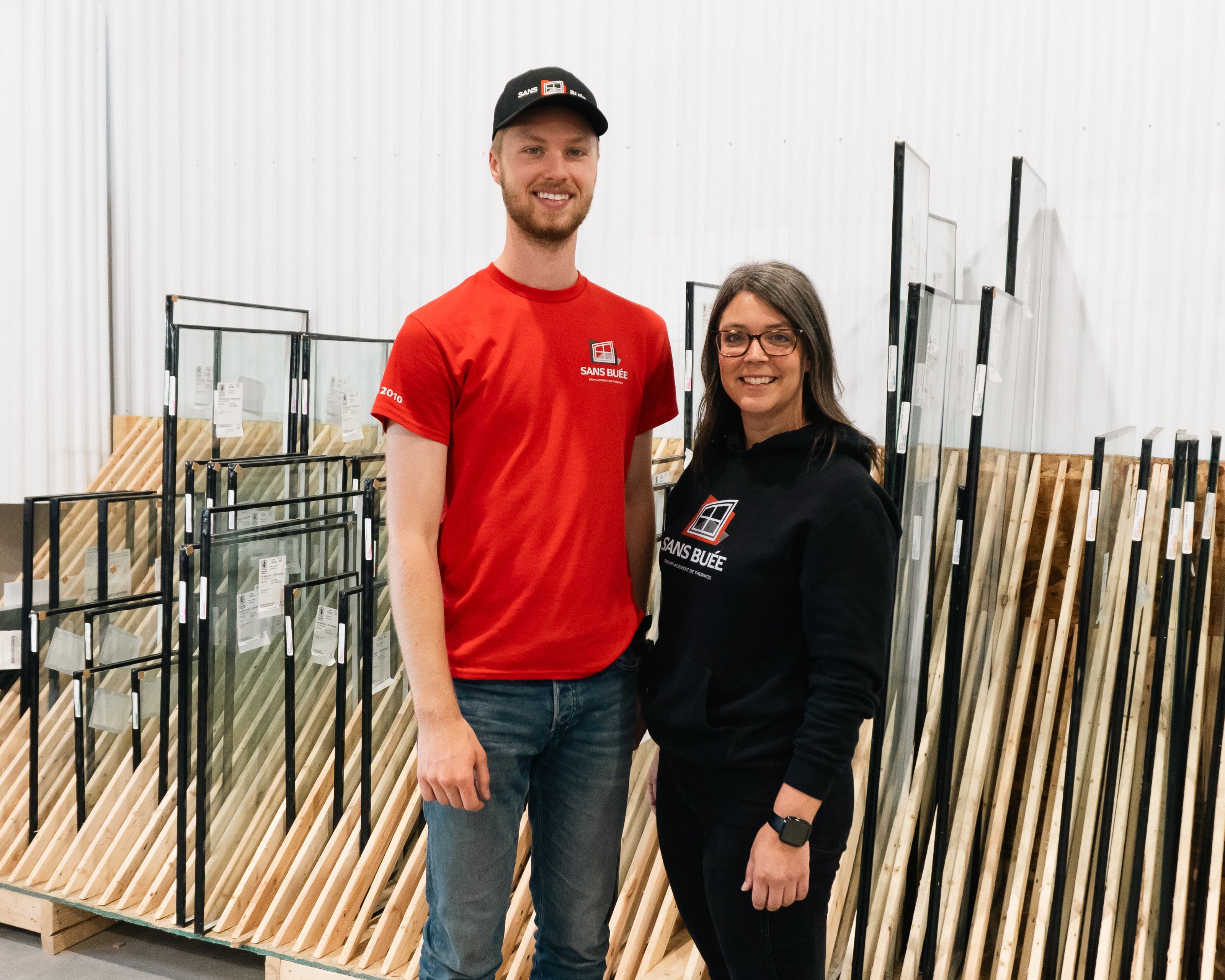 Two people standing in a warehouse with wooden pallets in the background